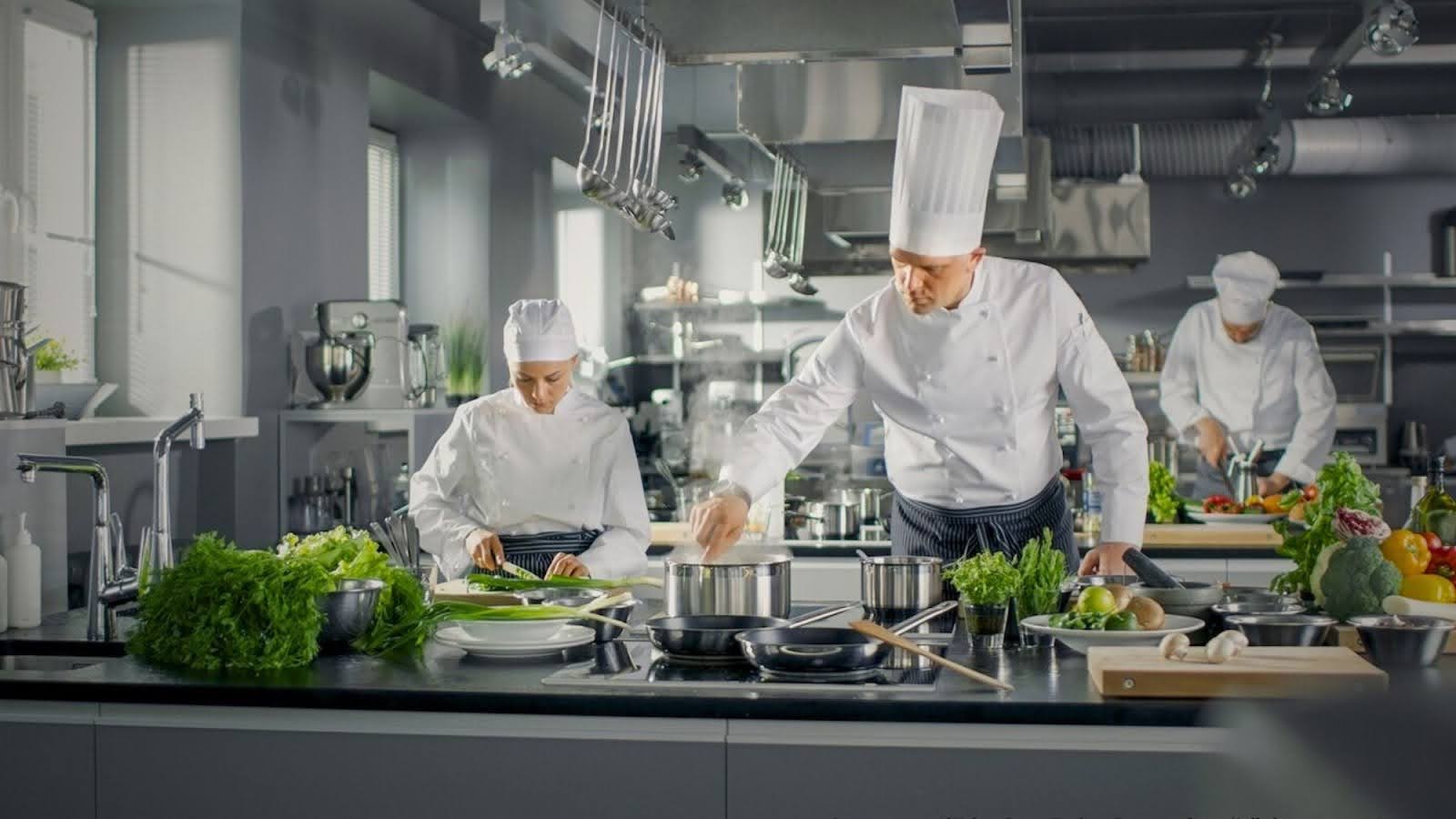 Commercial kitchens chefs busy cooking in surrounded by essential equipments