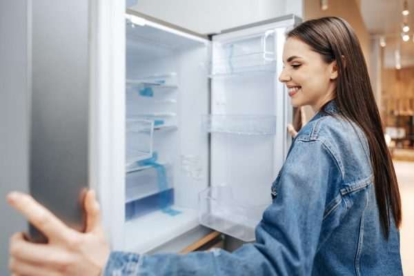 How to Clean and Maintain Your Freezer for Optimal Performance? Woman in overalls watering plants in a garden, promoting sustainable living for improved mental well-being