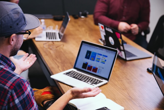 Group of people discussing website design and strategies with laptops in a meeting room.