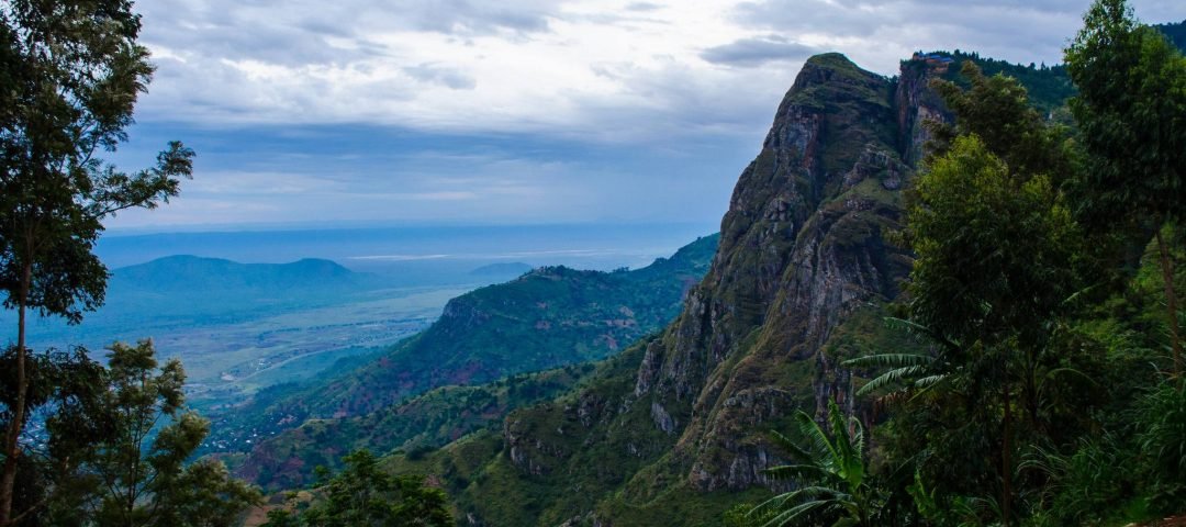 Scenic view of Usambara Mountains with local villagers walking along a trail during a cultural tour.