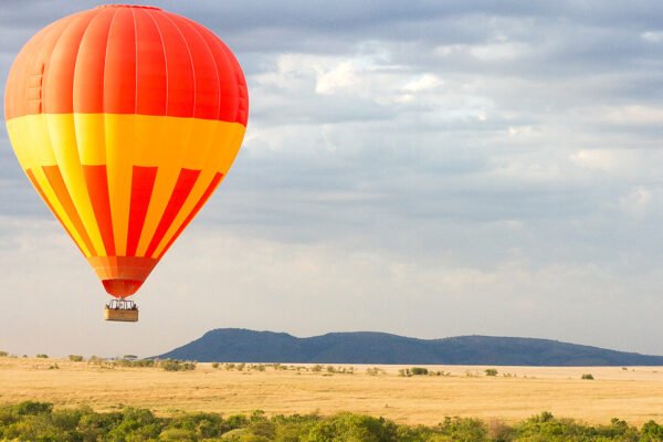 Flying hot-air balloon safari floating above the African savannah at sunrise
