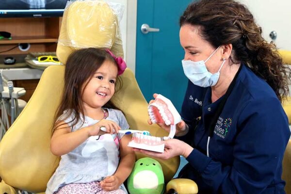 6 Tips For Preparing Kids For Their Dental Appointments Child smiling at a dentist during a dental appointment.