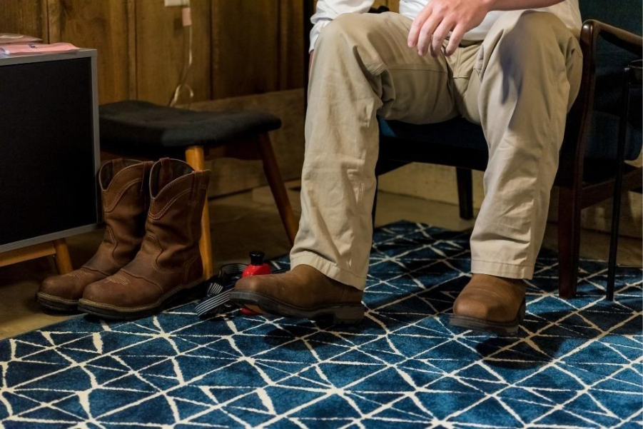 
Closeup shot of boots and a male sitting on a chair