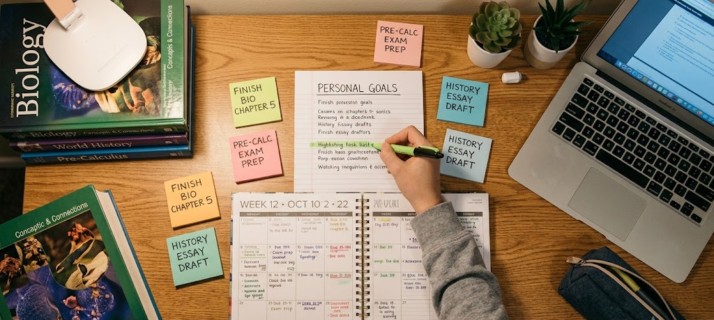 Organized study desk with goal lists, calendar, and sticky notes showing student academic planning.
