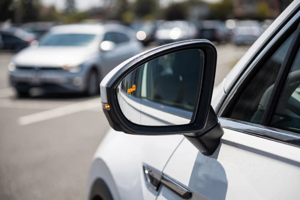  Volkswagen Tiguan side mirror showing active blind spot monitor warning light with car approaching in blind spot for safety technology