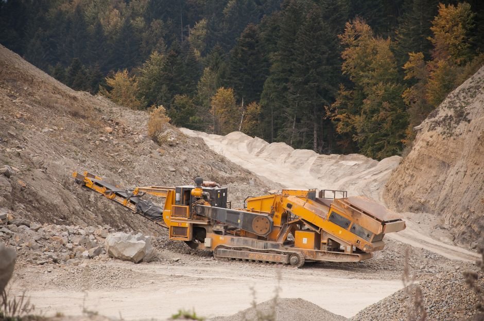 Heavy forestry equipment machinery lined up at a dealer lot with forested mountains in the background